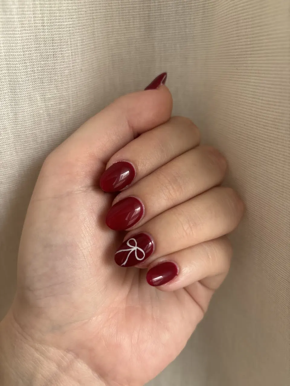Deep red nails with a bow accent